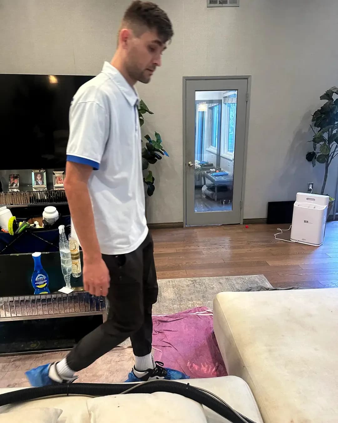 Young man in a white polo and dark pants stepping forward indoors.